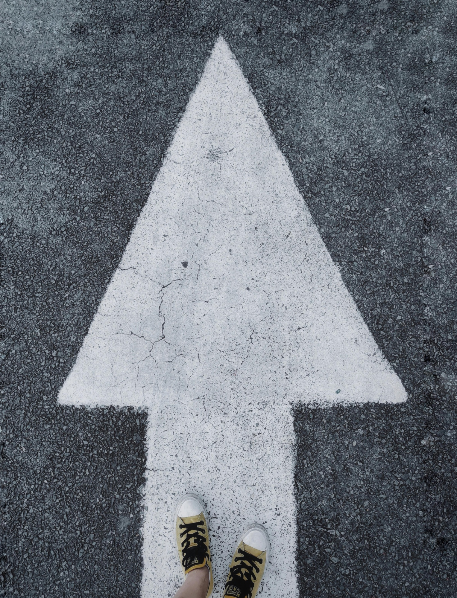 Image of an arrow on the ground with a feet stood looking forwards