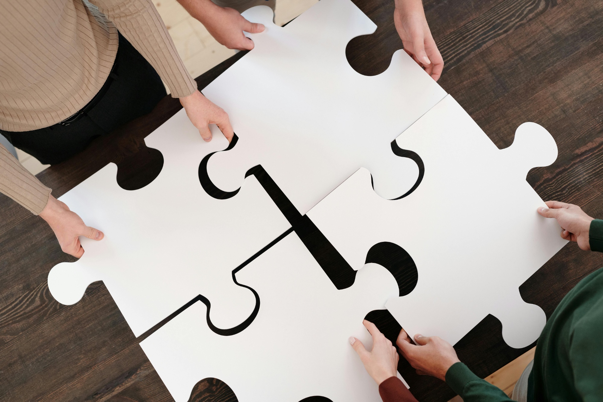4 people holding 4 jigsaw pieces, putting them together