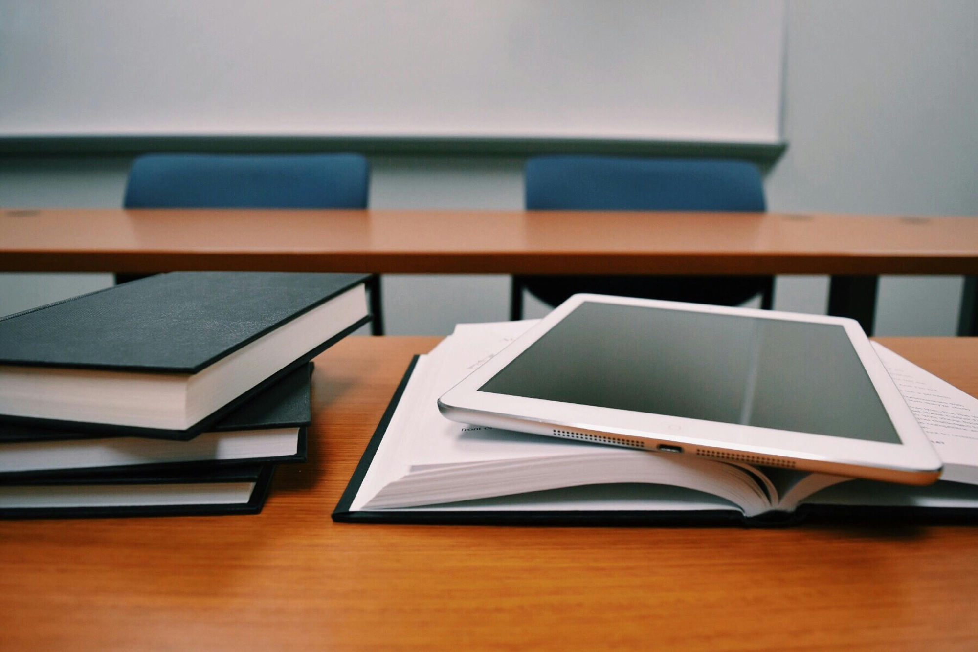 Books and a tablet resting on a school desk
