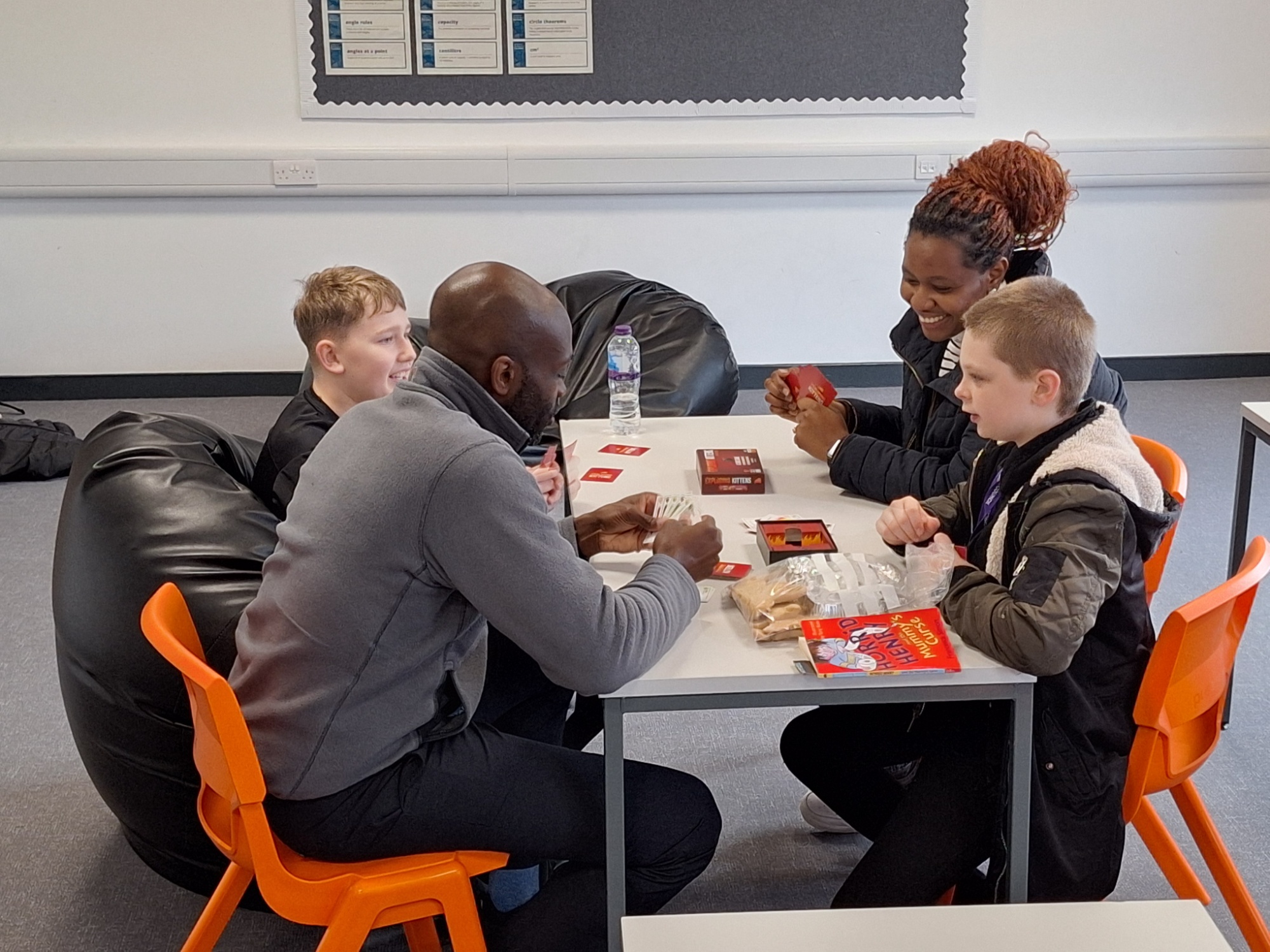 Maths lesson with 2 students and 2 staff members sitting around a table playing games